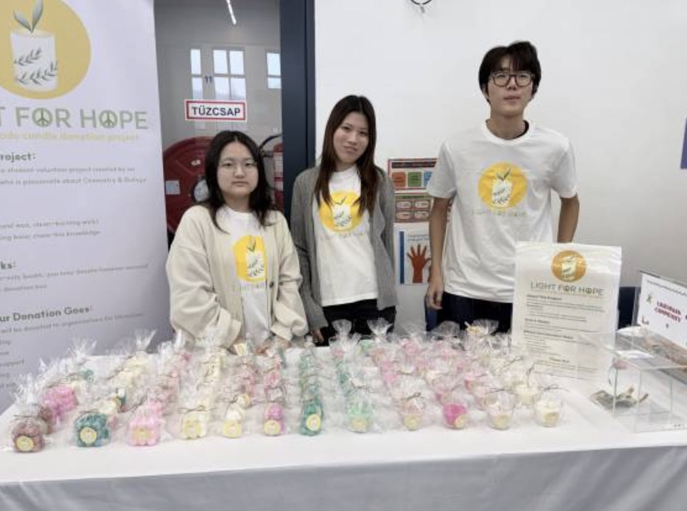 Hyunjin Choi standing at a Light for Hope fundraising booth with student volunteers